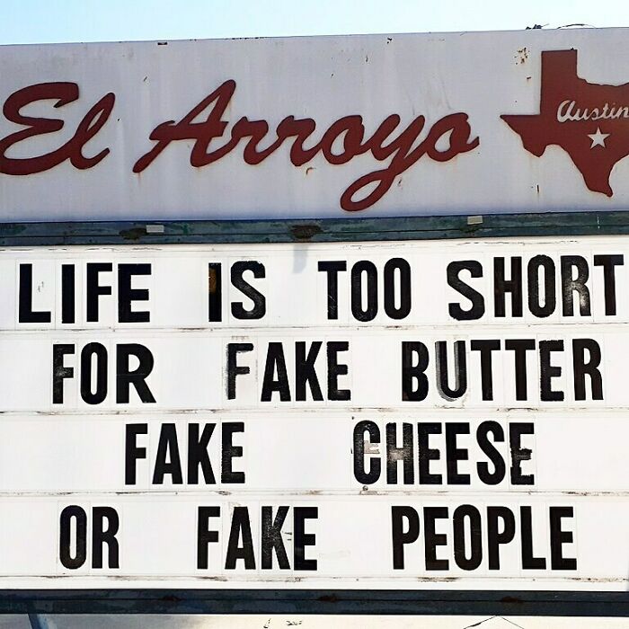 Restaurant sign with humorous message about avoiding fake butter, cheese, and people.