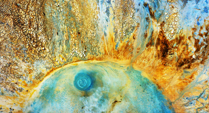 Aerial view of a colorful geothermal hot spring with c*****d earth and vibrant mineral deposits, Environmental Photographer award.