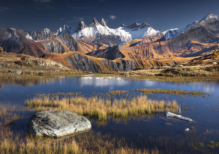 Colorful fall landscape in the Alps with autumn foliage, rocky mountains, and a reflective lake captured by a mountain photographer.