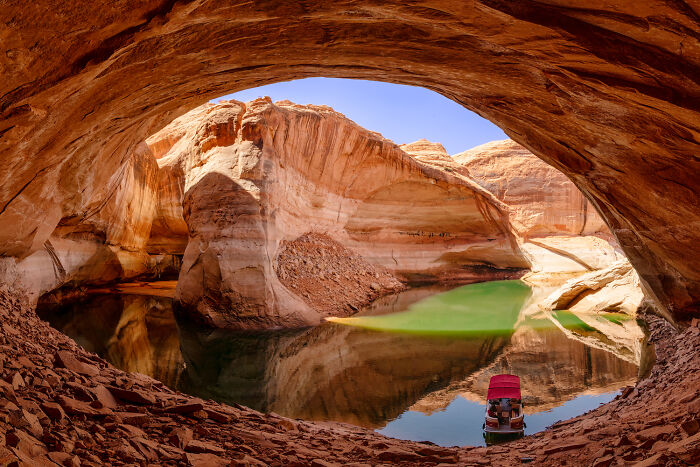 Scenic desert canyon with reflective water and boat, highlighting natural beauty in the Environmental Photographer of the Year contest.