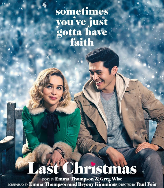 Scene from "Last Christmas," a couple sitting on a bench with snow falling, capturing festive holiday spirit.