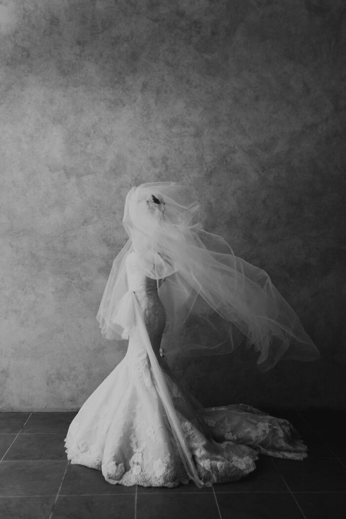 Bride in a flowing veil and lace wedding dress captured in a dramatic black and white wedding photographer submission.