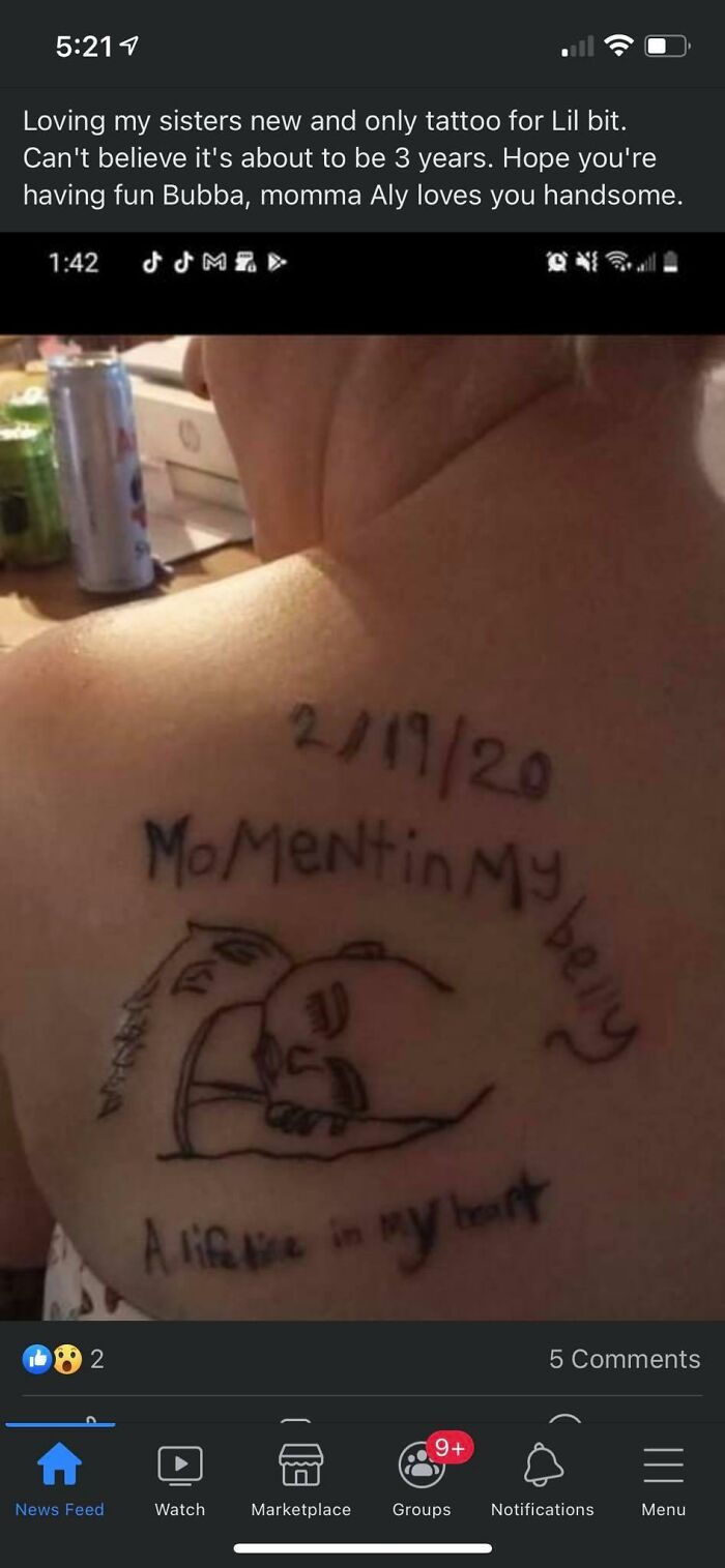Back tattoo with text "MoMent in my belly, a lifetime in my heart" and date, showcasing a questionable tattoo design.