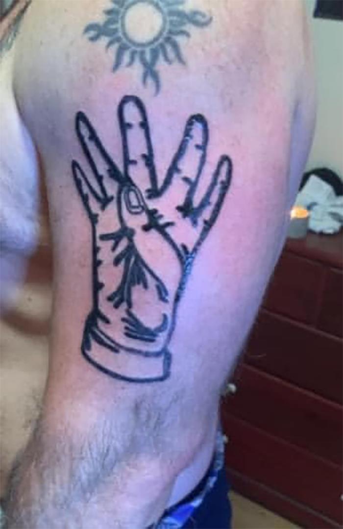 Poorly done tattoo of a hand on an arm, featuring a sun symbol above. Bad tattoo example for inkshaming.