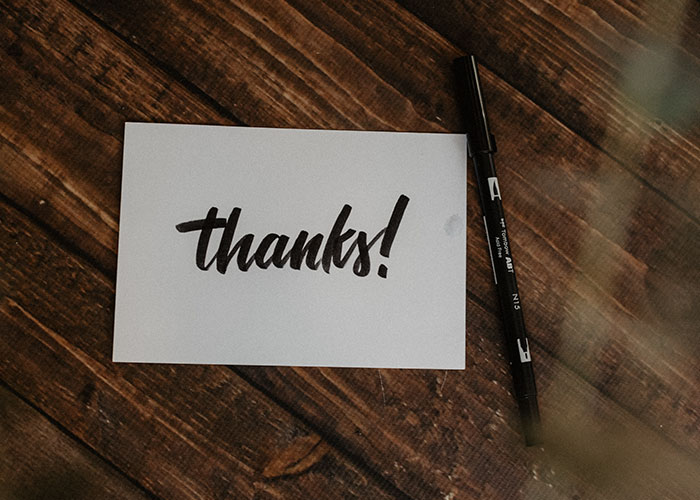 Handwritten thanks note on white paper with black pen on wooden table, reflecting Disney theme park employee experiences.