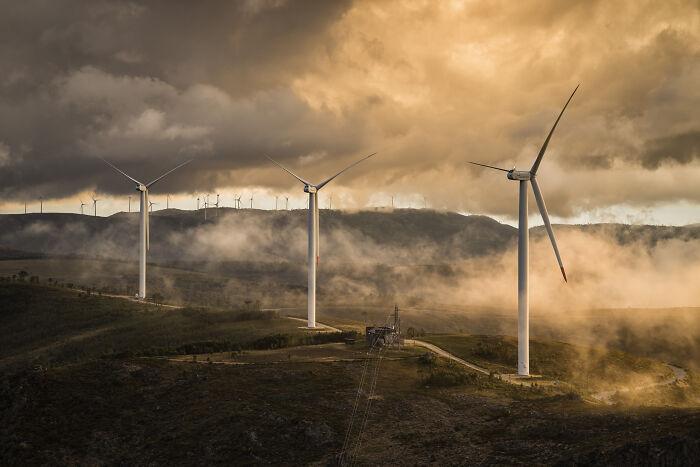 Wind turbines on a misty hill at sunset captured by Environmental Photographer of the Year 2021 finalists.
