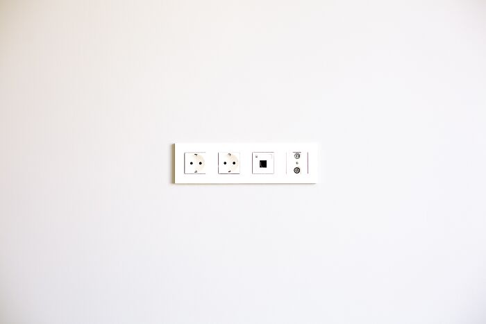 A white wall with multiple electrical outlets and ports in a row, illustrating common hiding spots burglars target.
