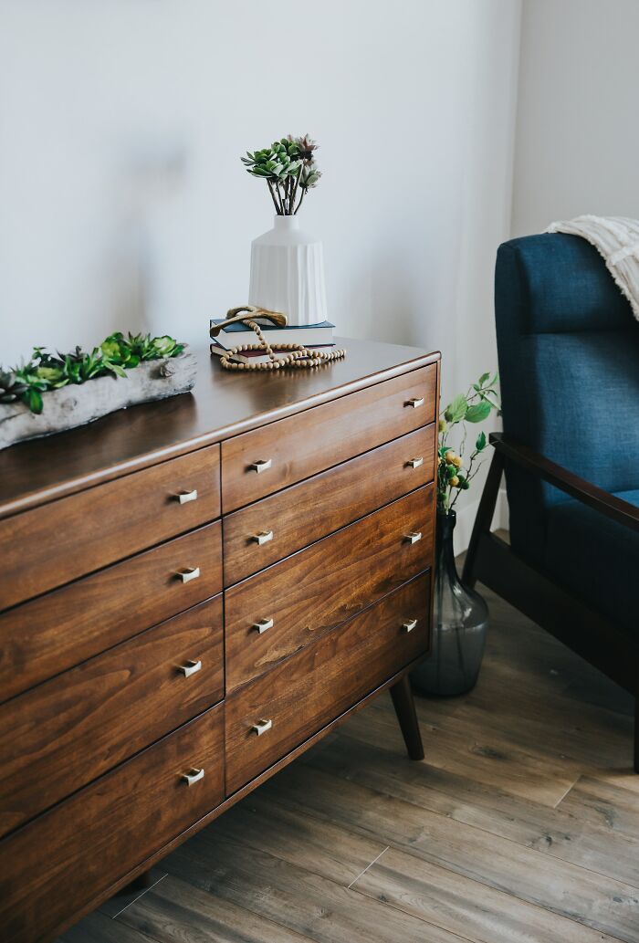 Mid-century wooden dresser with plants and decor, illustrating where you should never hide your stuff according to ex-burglars.