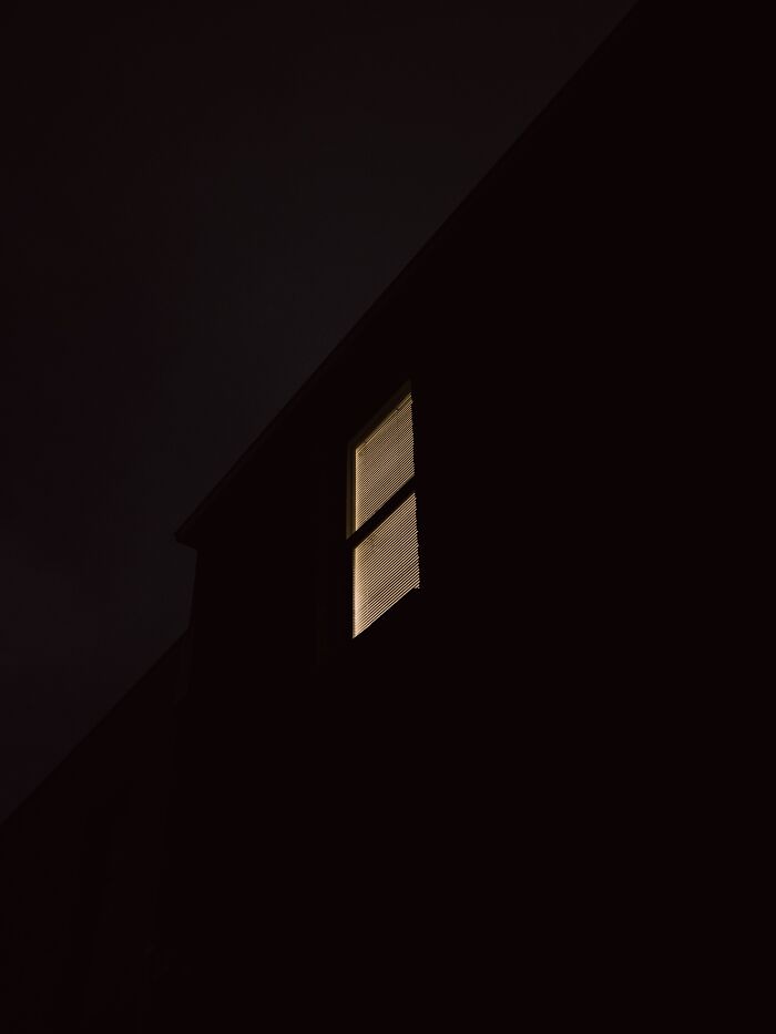 House exterior at night with a single illuminated window, illustrating tips from ex-burglars on where not to hide your stuff.