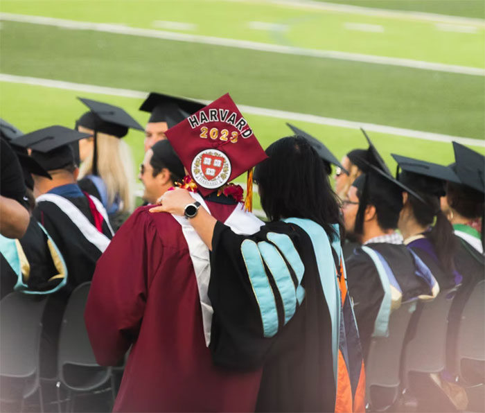 Graduate in Harvard cap and gown with mentor celebrating success, representing gifted people sharing life outcomes.