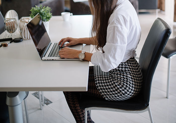 Woman labeled gifted working on laptop at modern office desk, focused and typing in a professional setting.