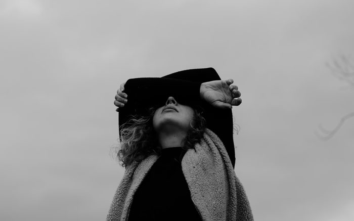 Black and white photo of a person covering their eyes with arms, reflecting on life after being labeled gifted.