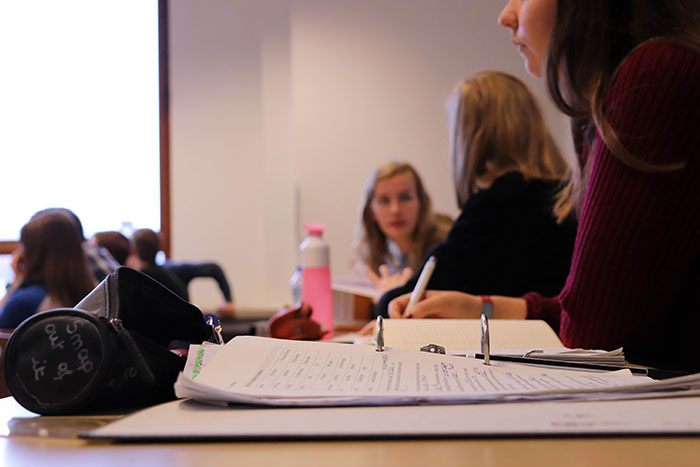 Students in classroom taking notes with open binder and paper, representing gifted individuals in an educational setting.