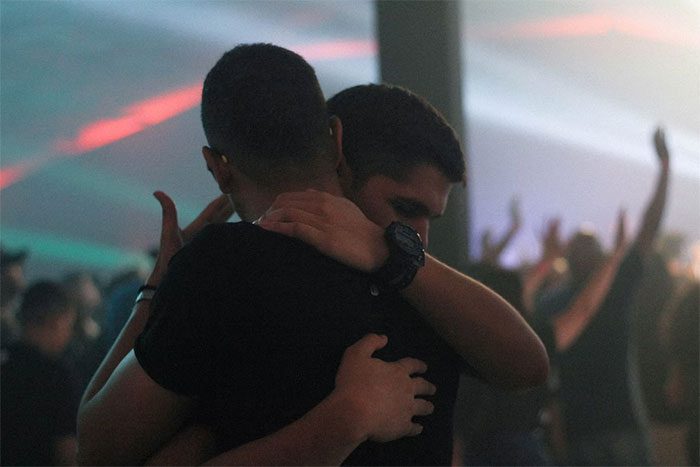 Two people embracing in a dimly lit crowd, symbolizing support and connection among gifted individuals.