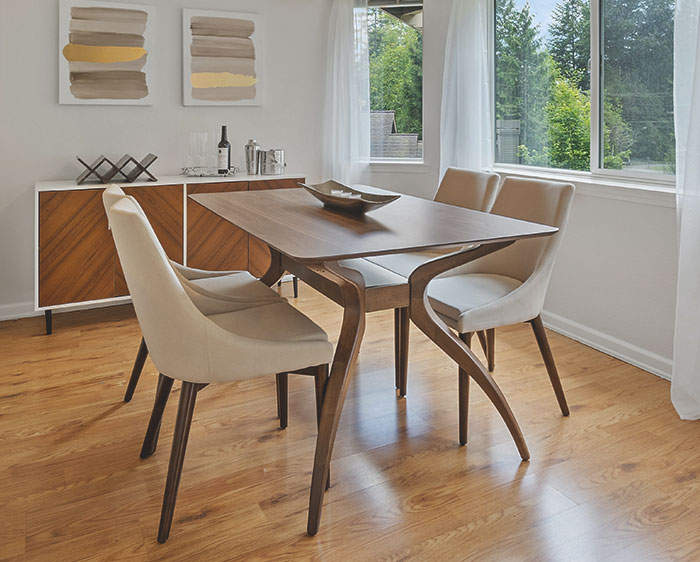 Modern dining room with wooden table and chairs, bathed in natural light, illustrating quiet good deeds kept in secret.