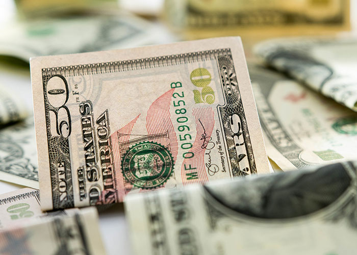 Close-up of a fifty-dollar bill among other currency, symbolizing secret good deeds involving money and generosity.