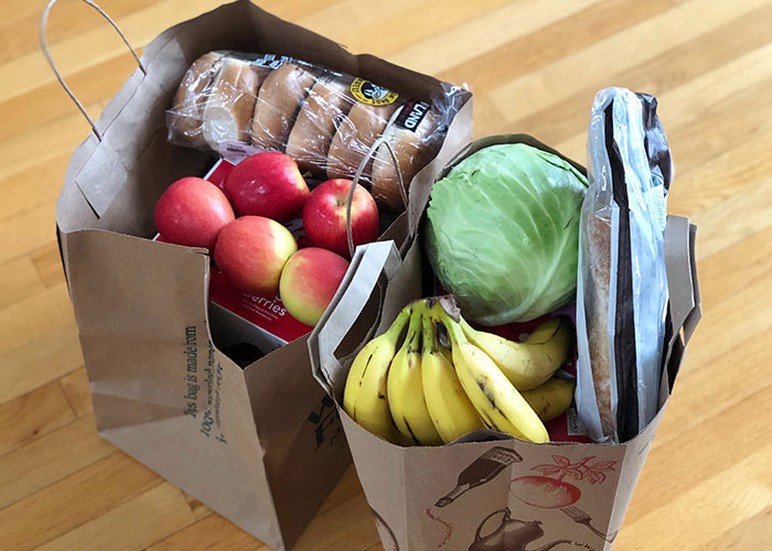 Two paper grocery bags filled with fresh fruits and vegetables representing good deeds kept in secret.