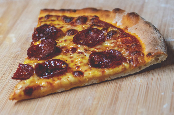 Slice of pepperoni pizza on a wooden board, representing one of the good deeds people have been keeping in secret.