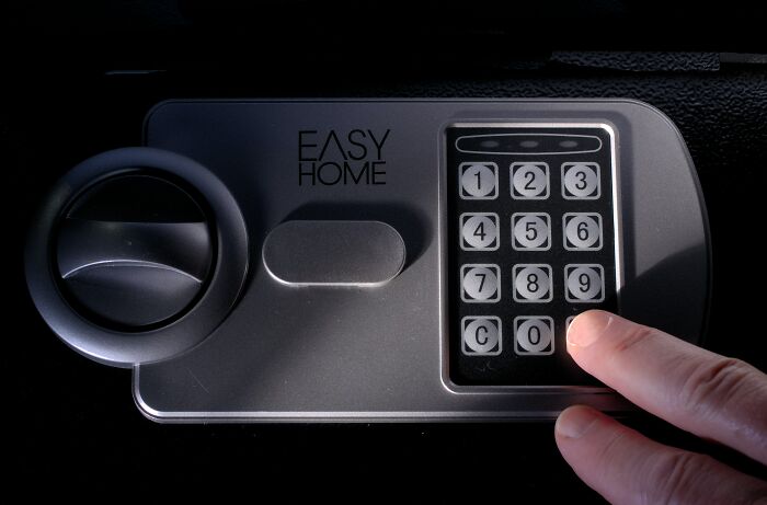 Close-up of a person entering a code on a home safe keypad, illustrating tips from ex-burglars on where not to hide valuables.