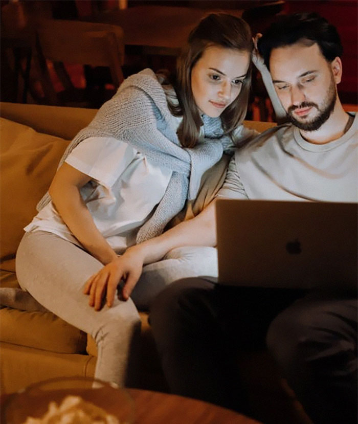 Couple sitting on a couch together, focused on a laptop, illustrating insights about married life and relationships.