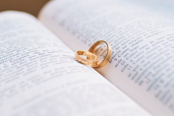 Two gold wedding rings placed on an open book, symbolizing married life and relationships insights.