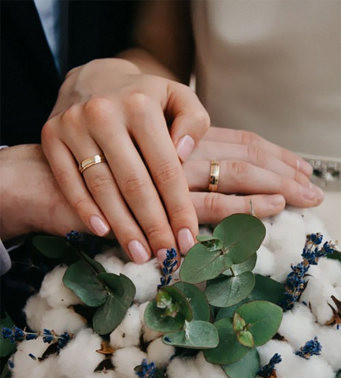 Close-up of married hands with wedding rings resting on a floral bouquet, symbolizing married life insights for unmarried people.