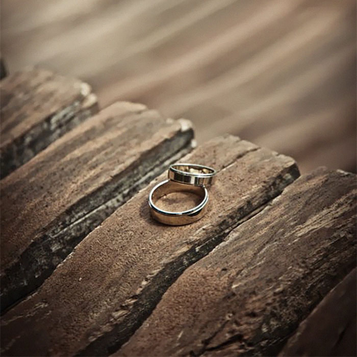 Two silver wedding rings resting on weathered wooden surface symbolizing married life insights and advice.
