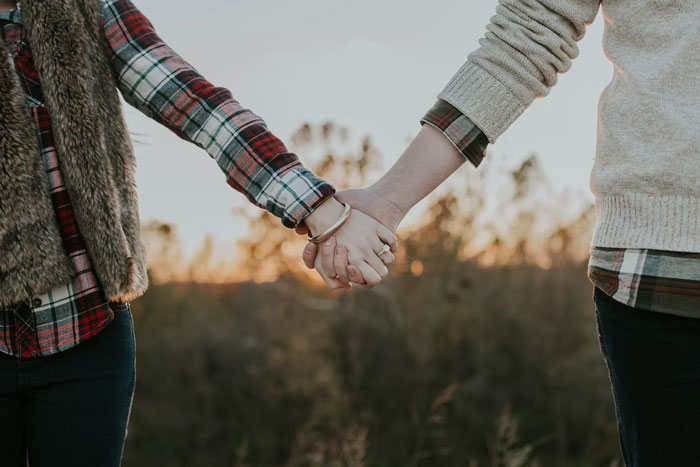 Couple holding hands outdoors at sunset, symbolizing married life and what unmarried people want to know about marriage.