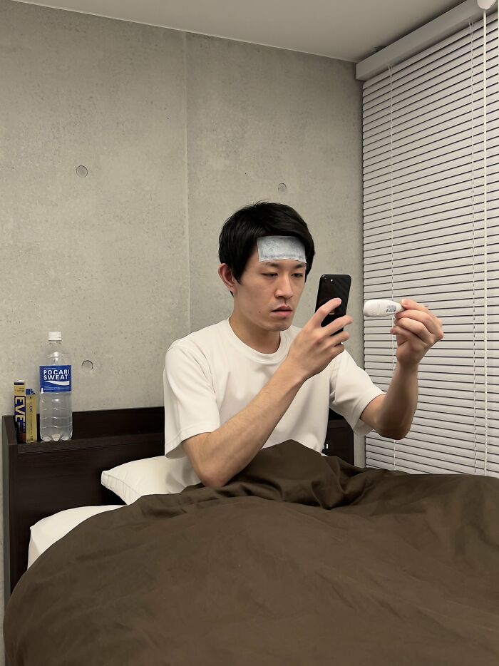 A Person With A Fever And In Pain Trying To Look On Their Symptoms Online