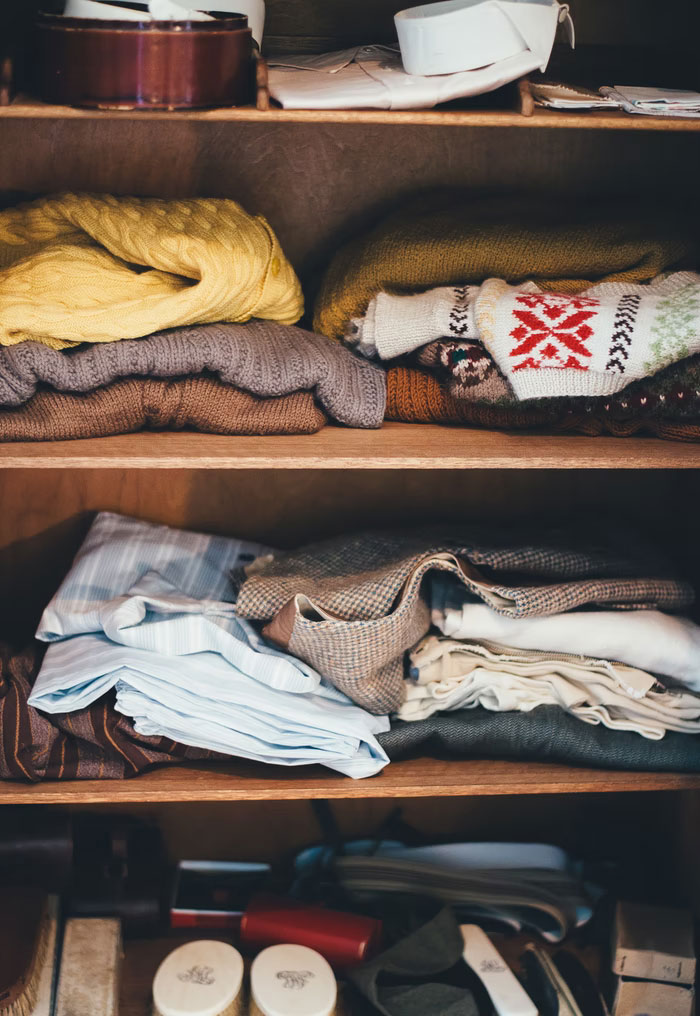 Closet shelves with folded sweaters and shirts illustrating modern home trends and storage annoyances shared by people.