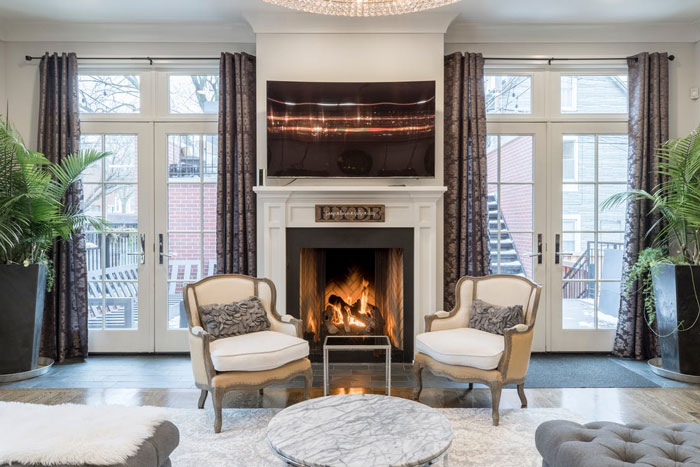 Cozy living room with fireplace and modern home trends including symmetrical armchairs and neutral decor.