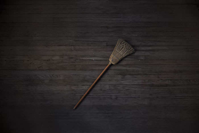 Broom on dark wooden floor representing annoying modern home trends many people find frustrating.