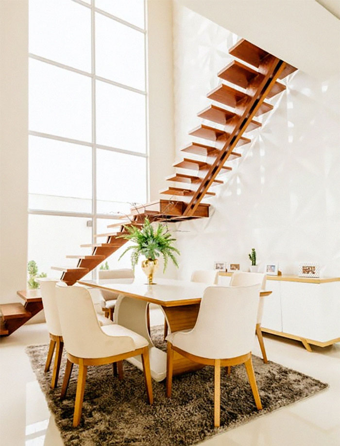 Bright dining area with minimalist furniture and a floating wooden staircase showcasing modern home trends.