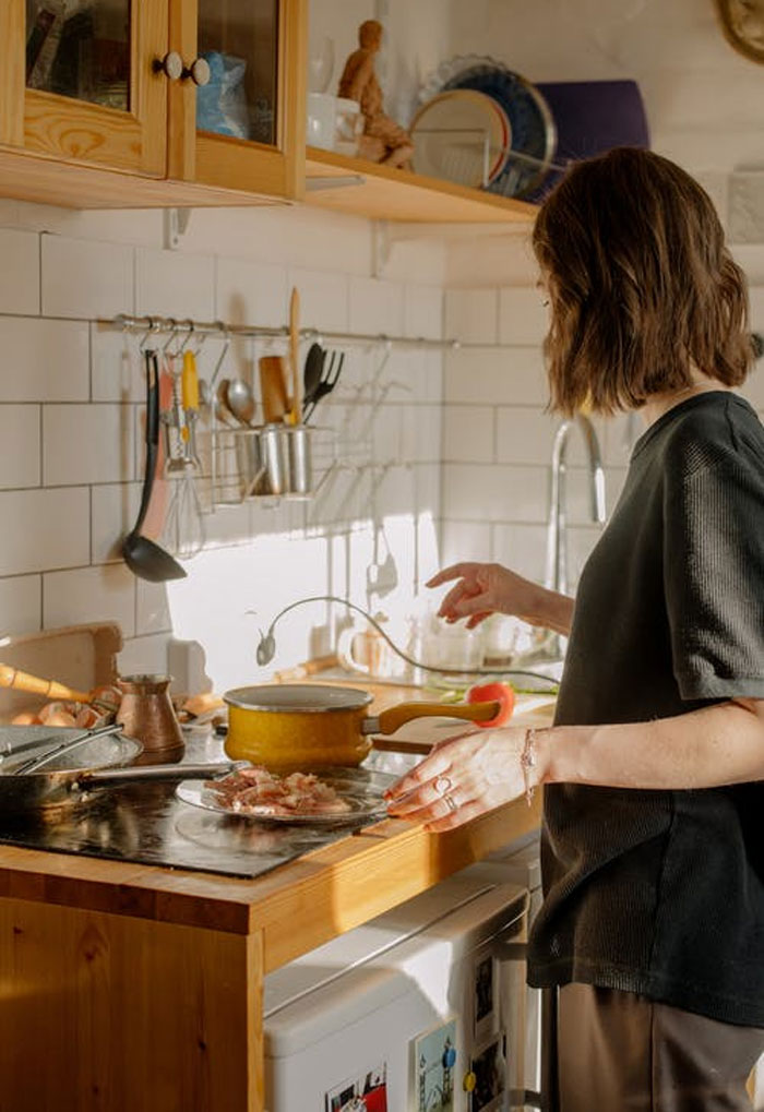Person cooking in a kitchen with wooden counters and white tile backsplash showing modern home trends.