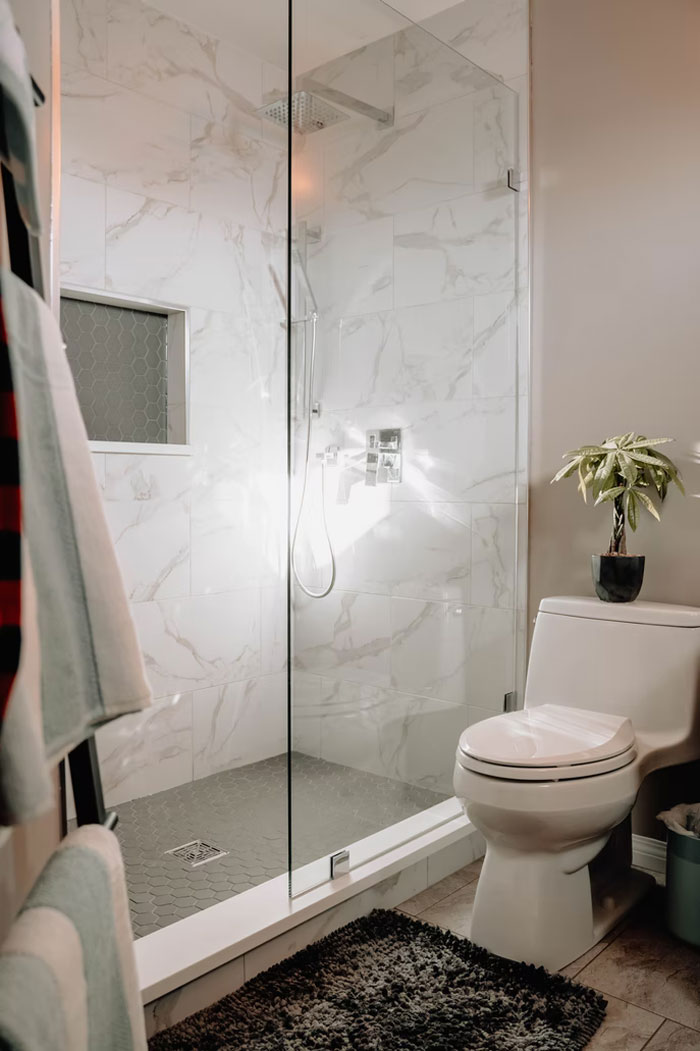 Modern bathroom with glass shower enclosure and white marble tiles highlighting common modern home trends.