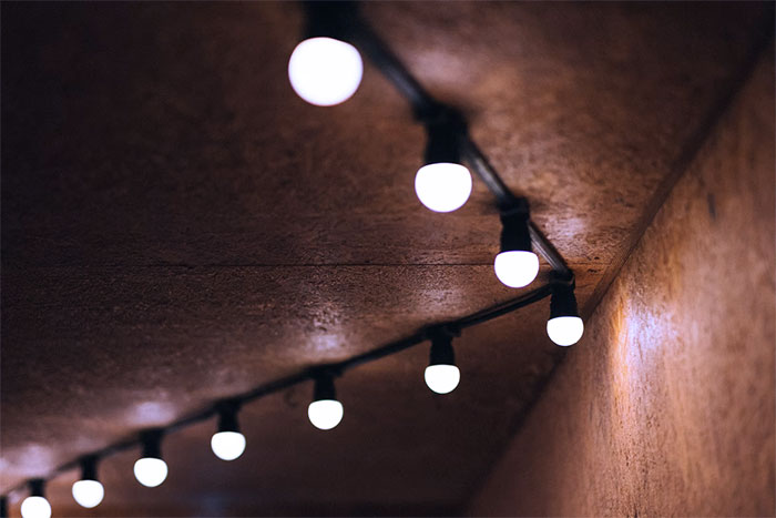 String of modern home trend light bulbs hanging on textured ceiling, highlighting popular annoying design features.