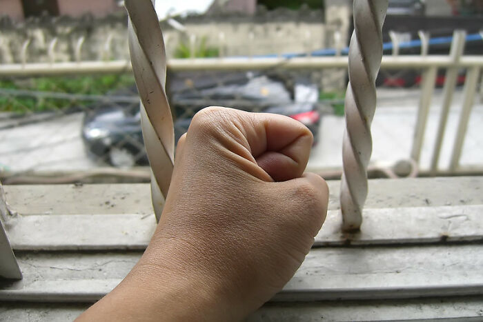 Hand clenched into a fist gripping metal bars, representing former prisoners sharing insights about incarceration experiences.