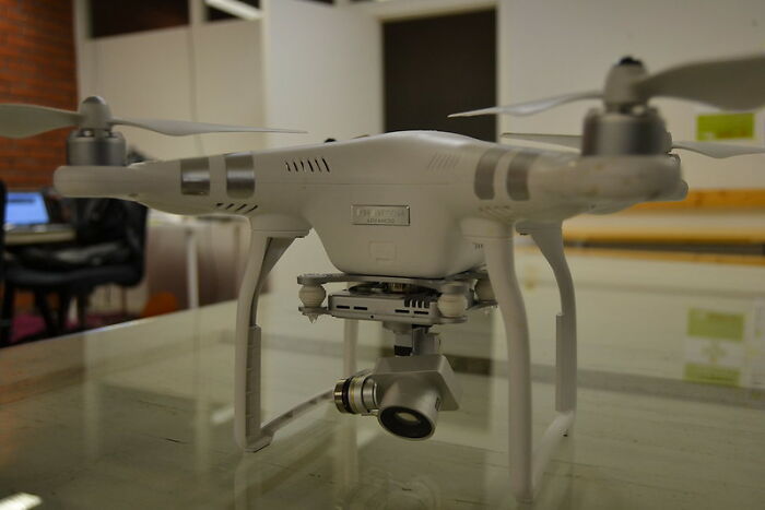 White quadcopter drone with camera on a table, illustrating technology used by former prisoners to share incarceration experiences