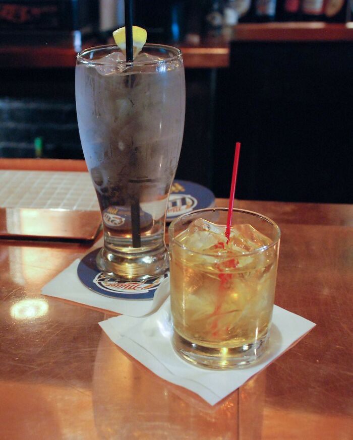 Two drinks on a bar counter with ice and straws, illustrating bartenders sharing insights on drink orders and personalities.