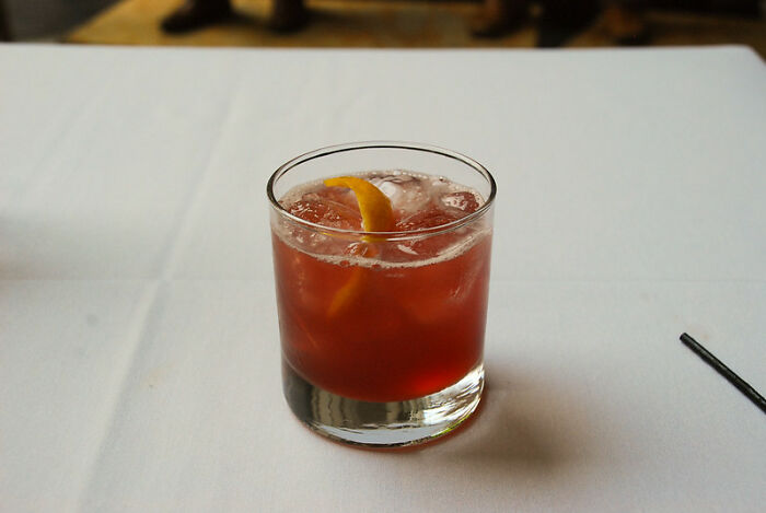 Cocktail on a white table with an orange peel garnish, illustrating bartenders sharing drink orders and personality insights.