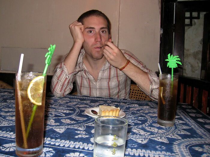 Man sitting at a table with two drinks and dessert, illustrating bartenders in this online group sharing drink order meanings.