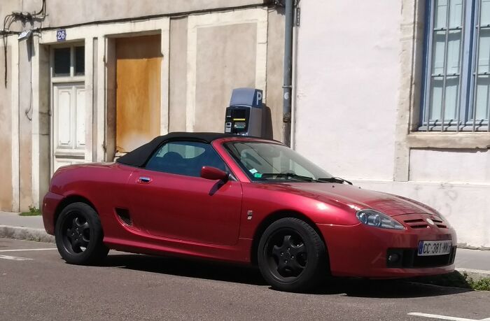 Red convertible car parked on a street with buildings in the background, related to lawyers sharing big moments.