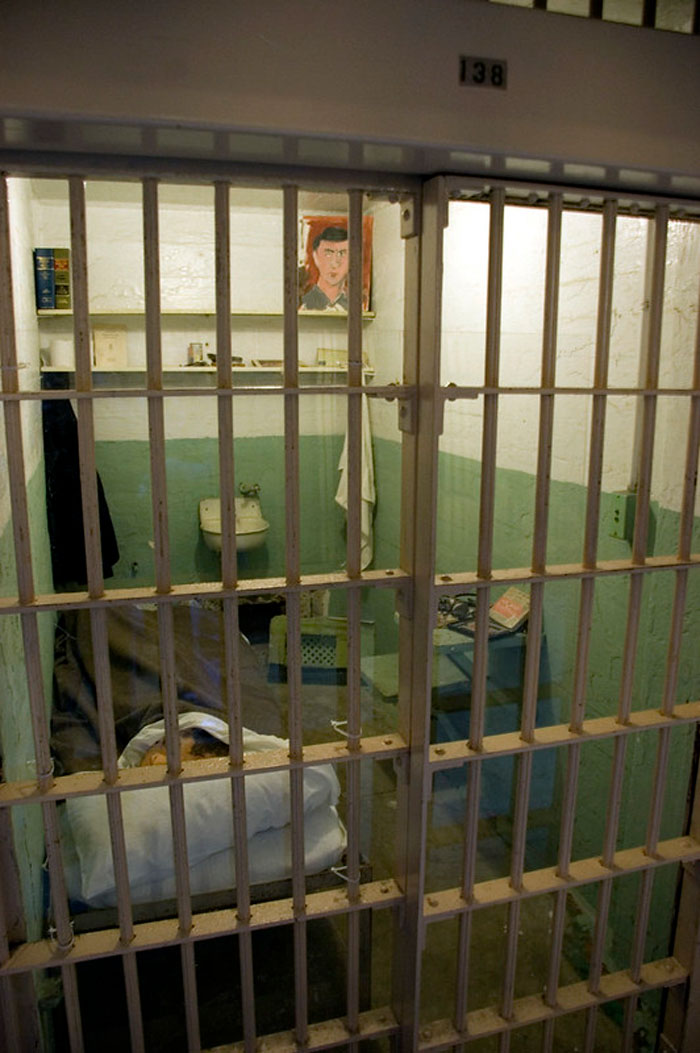 Prison cell interior with bars, bed, and sink illustrating life experiences of former prisoners about incarceration.