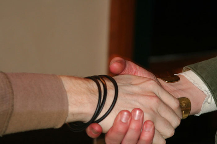 Handshake between former prisoners and friends symbolizing support and experiences shared about incarceration challenges.