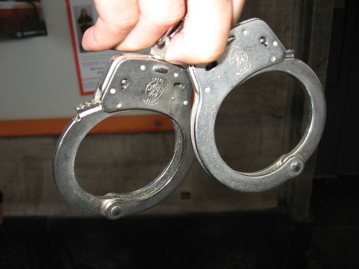 Hand holding metal handcuffs symbolizing challenges former prisoners face during incarceration and reentry.