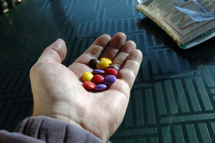 Hand holding colorful pills on table, symbolizing challenges former prisoners and families face during incarceration.
