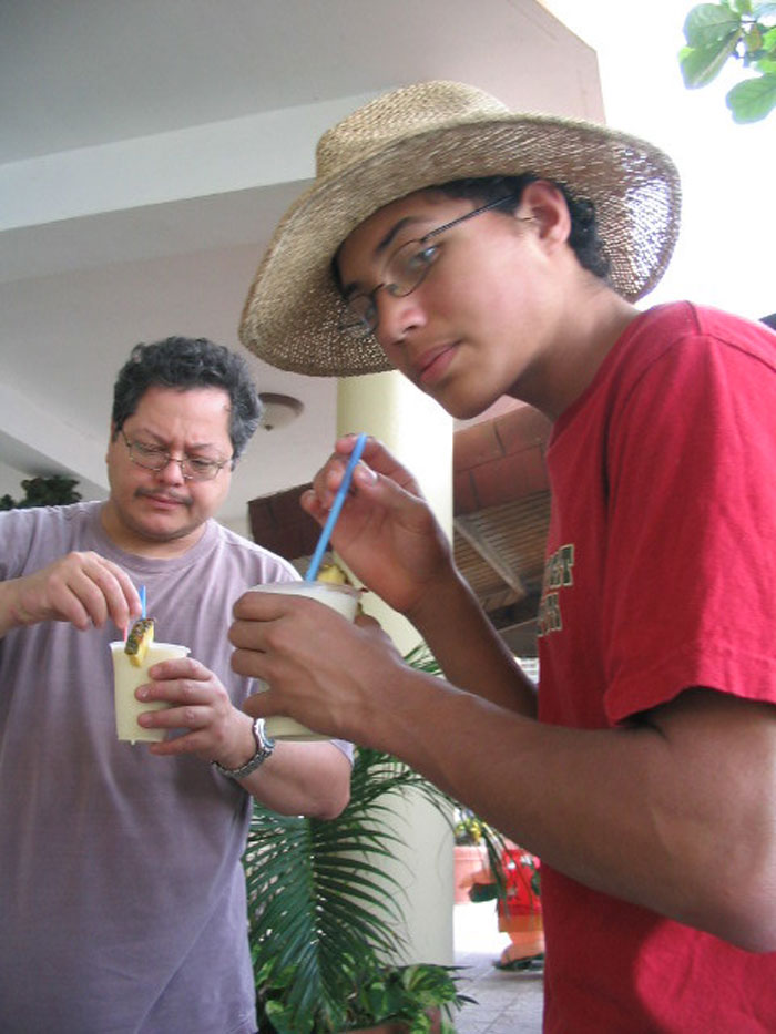 Two men enjoying tropical drinks with straws, illustrating bartenders in an online group sharing drink order insights.
