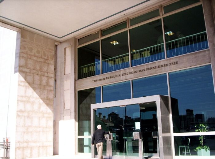 Man entering a modern courthouse building, representing lawyers in this online group sharing legal stories.