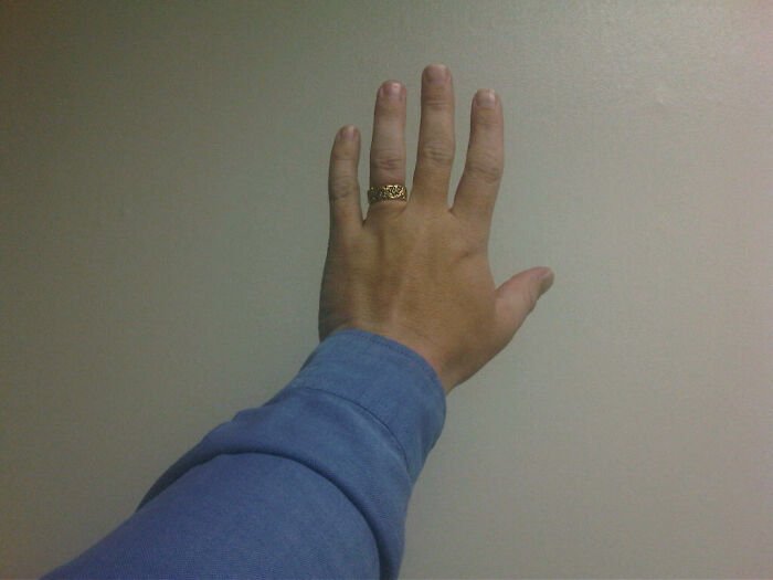 Hand raised against a plain wall, wearing a blue shirt and a gold ring, illustrating moments lawyers noticed big mistakes.