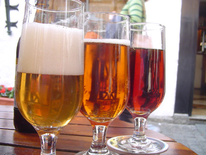 Three different beers served in glasses on a wooden table reflecting bartenders drink orders and personality insights.